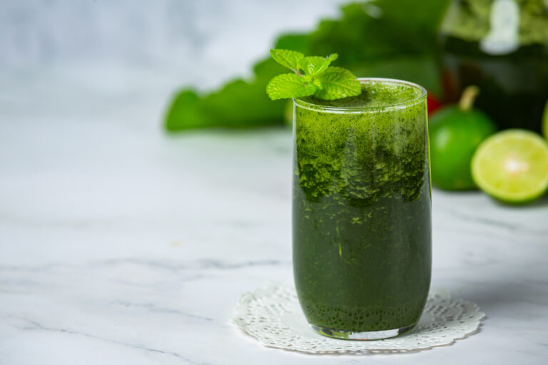 Copo de suco verde detox com couve, maçã e limão sobre a mesa