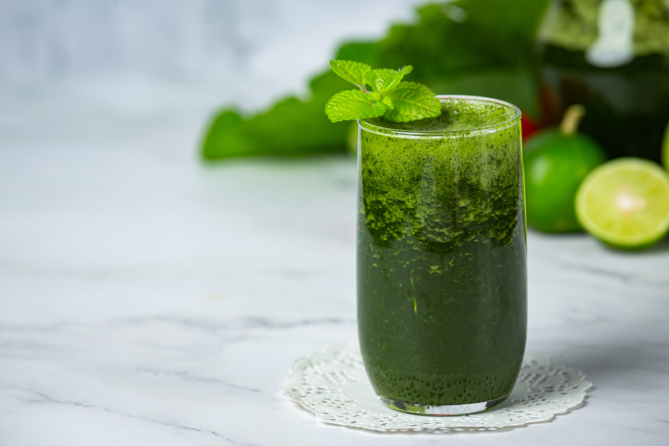 Copo de suco verde detox com couve, maçã e limão sobre a mesa